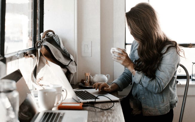 Girl sitting at desk while drinking coffee and writing