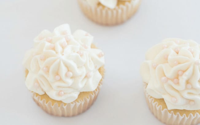 2 cupcakes with white icing on a white table