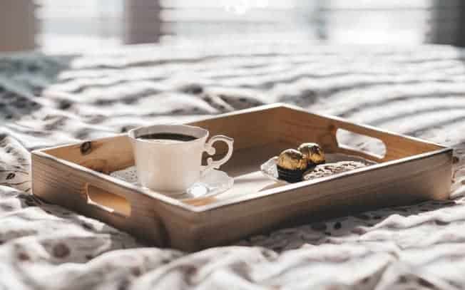 Tea and chocolates on a breakfast tray on a bed