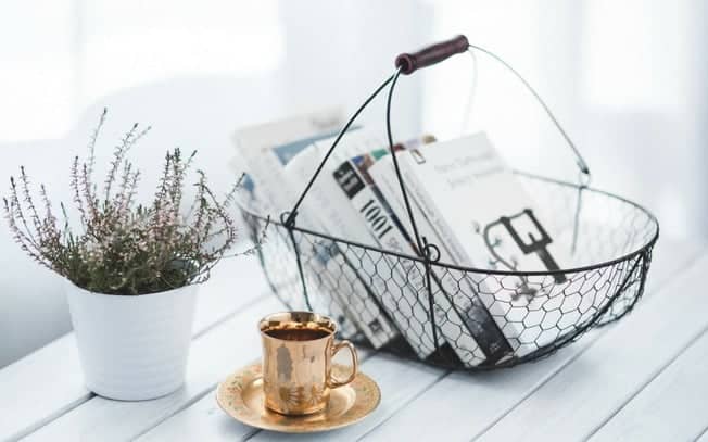 Books in a basket with a cup of tea and flowers