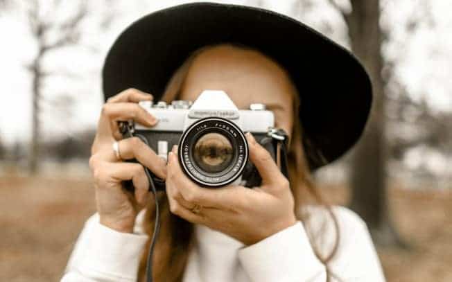 girl wearing hat and taking picture with her camera