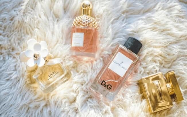 four perfumes laying on a white shag rug