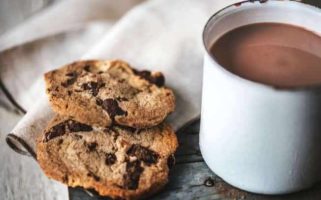 Two cookies beside a mug of hot chocolate