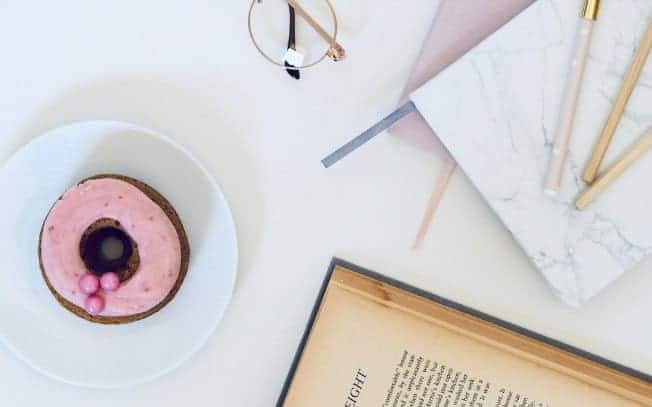 pink donut on a table beside a book and a notebook