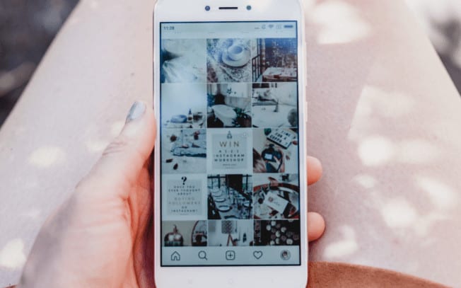 Girl with painted nails holding cellphone while looking at Instagram