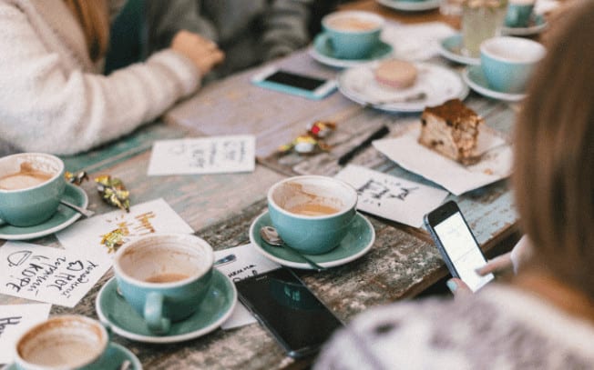 People sitting and drinking coffee at a picnic table