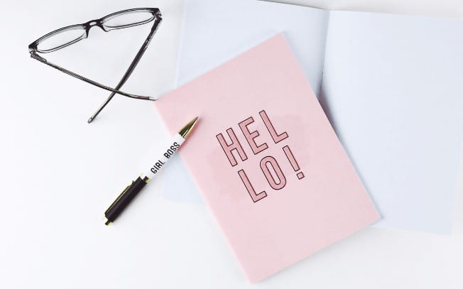 Pink notebook with pen and glasses