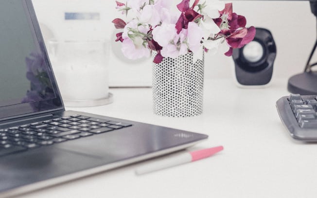 Laptop with pink and red flowers beside it