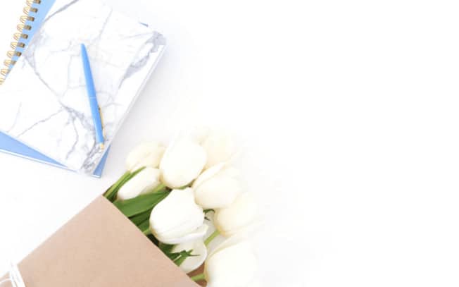 White flowers beside marble notebook