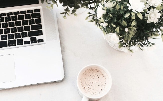 Laptop with coffee and flowers birds-eye view