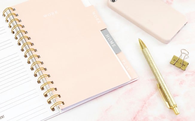 notepad and gold pen on pink marble table