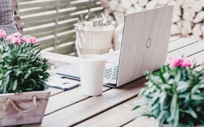 laptop and coffee mug on table with flowers