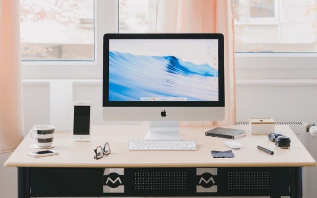 Laptop on a desk with tea and a phone beside it