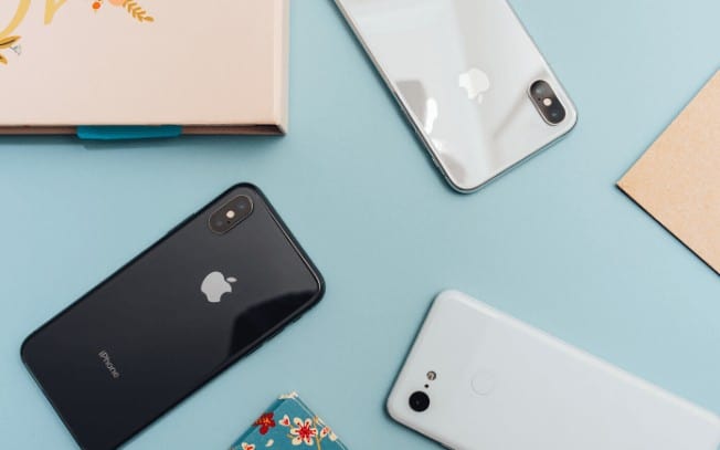 3 iPhones on a blue desk