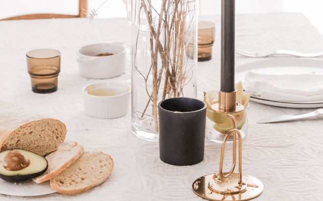 An avocado with bread and a candle on a white table