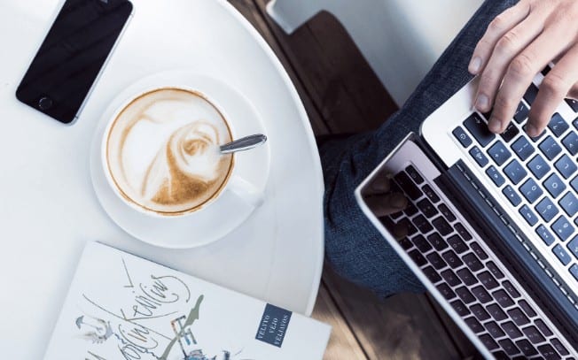 Latte and laptop on a white desk