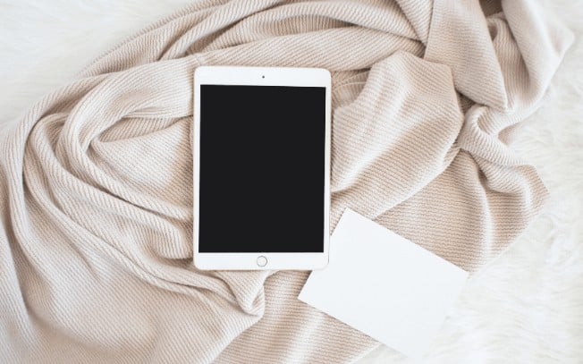 Photo of iPad and notebook on a cream color blanket