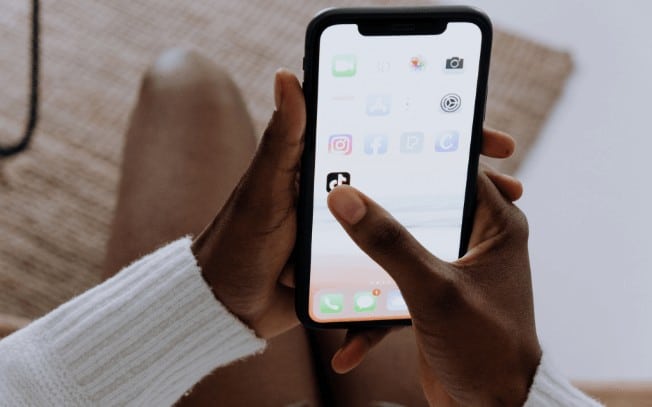 Picture of hands holding a cell phone and clicking on the TikTok app