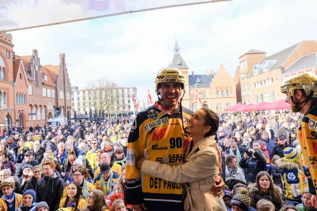 A hockey player and a woman in front of a crowd in Denmark.